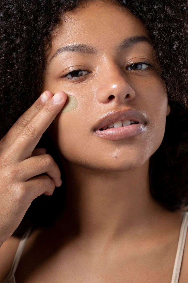 Portrait of beautiful black woman applying foundation